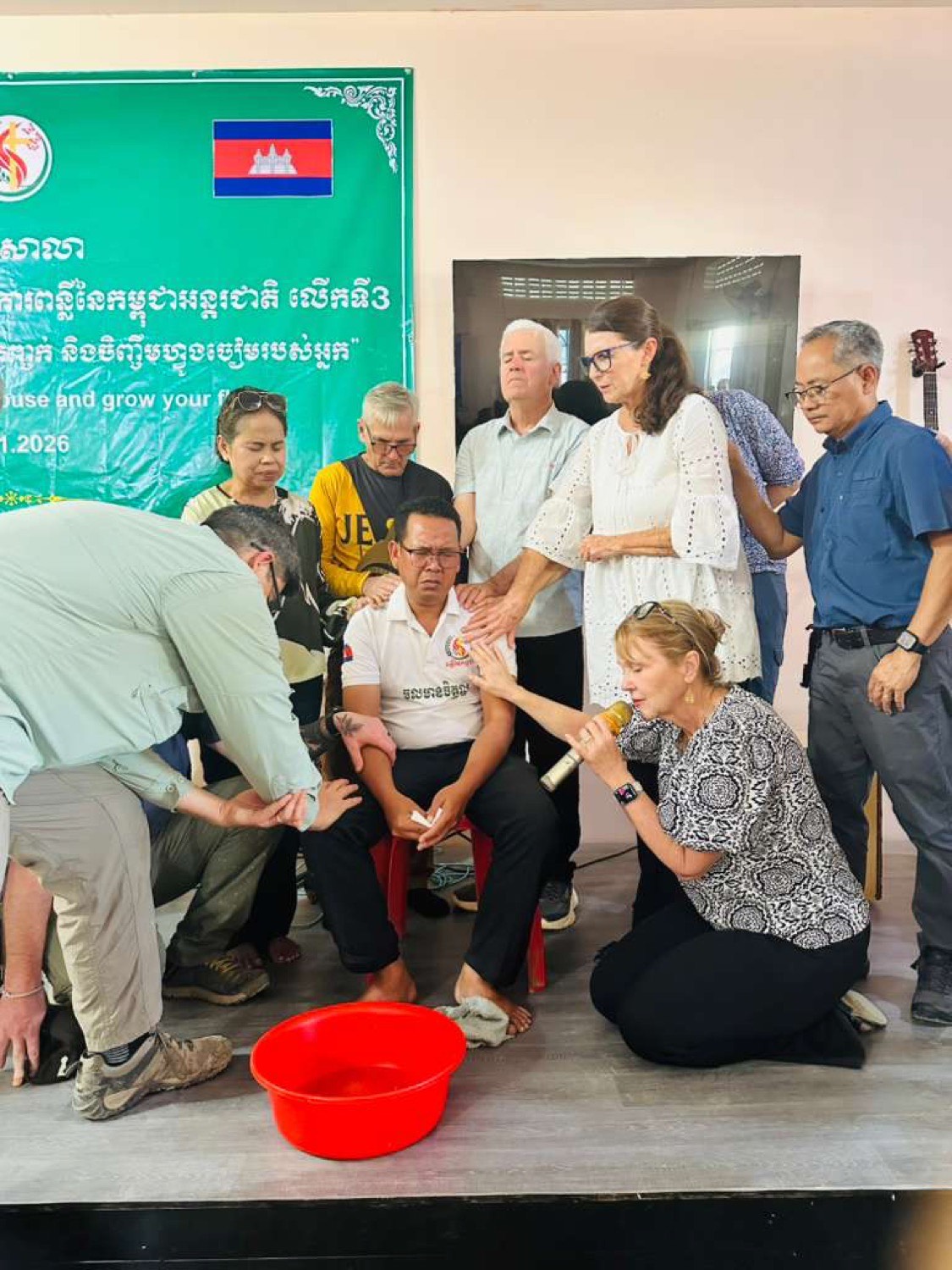 Local pastors and team members praying together over a Cambodian pastor during a leadership training