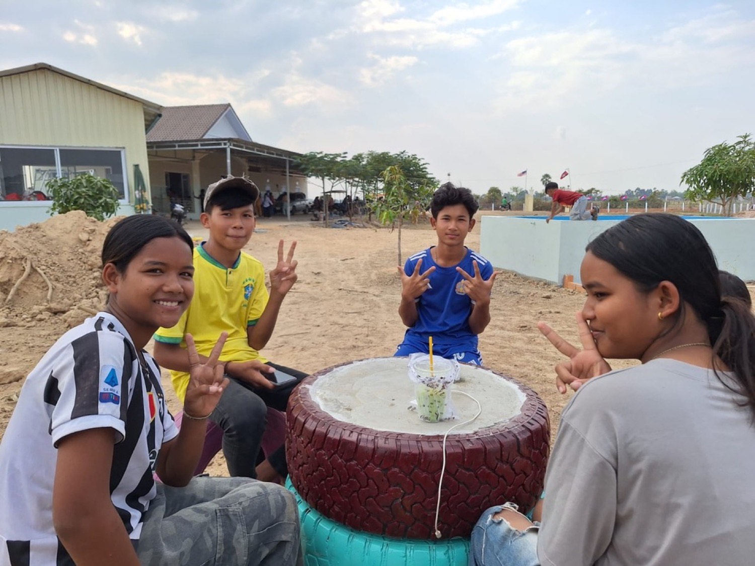 Teenagers gathered around a painted tire table outside the ministry building