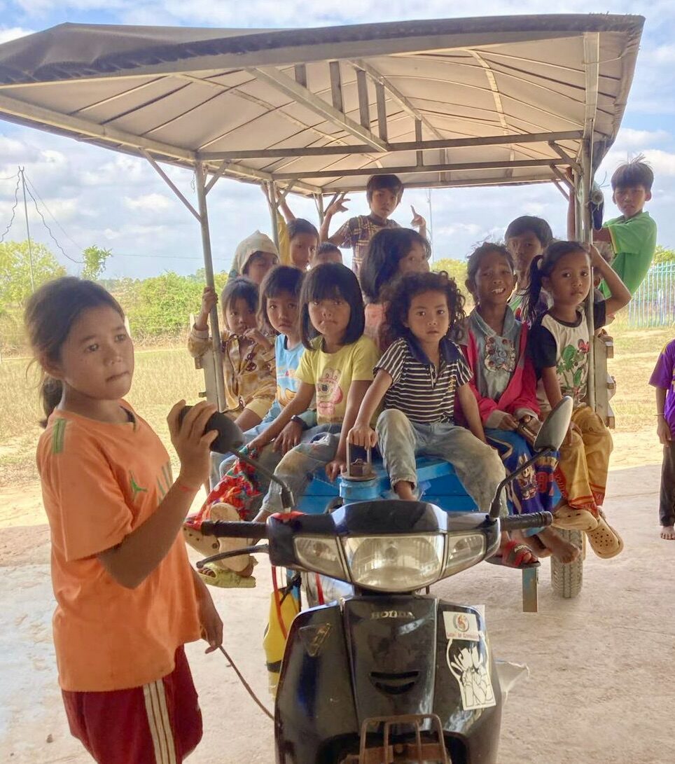 Children riding together in the motorbike cart that brings them to Light of Cambodia gatherings